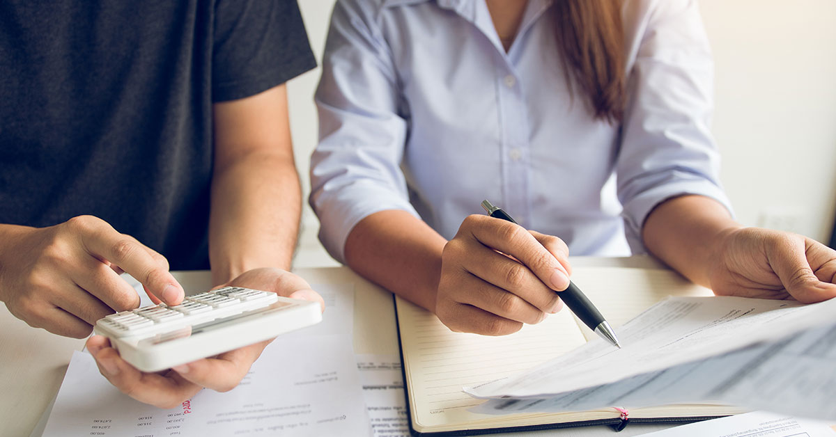 Couple sitting at a table calculating their debt-to-income ratio to determine how much they can spend on a new home.