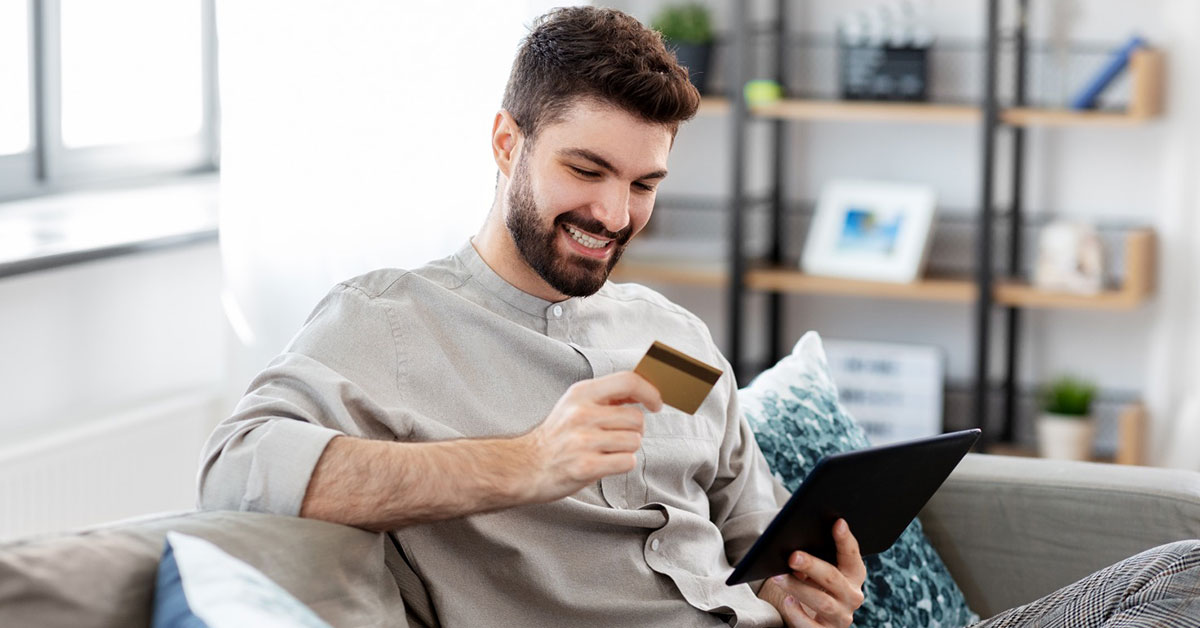 Man sitting using his credit card to make a purchase online