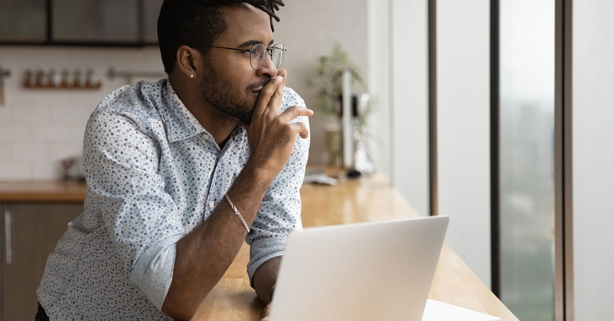 young man on a laptop thinking about his goals