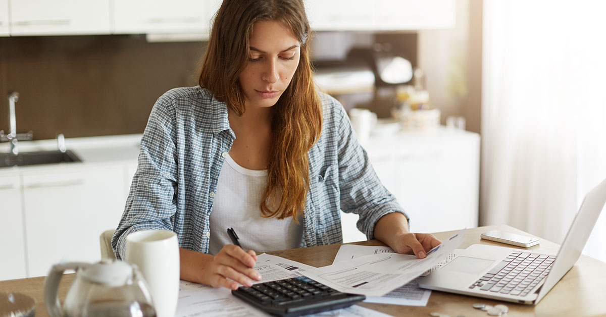 A woman sits at her kitchen table and goes through her financial paperwork.