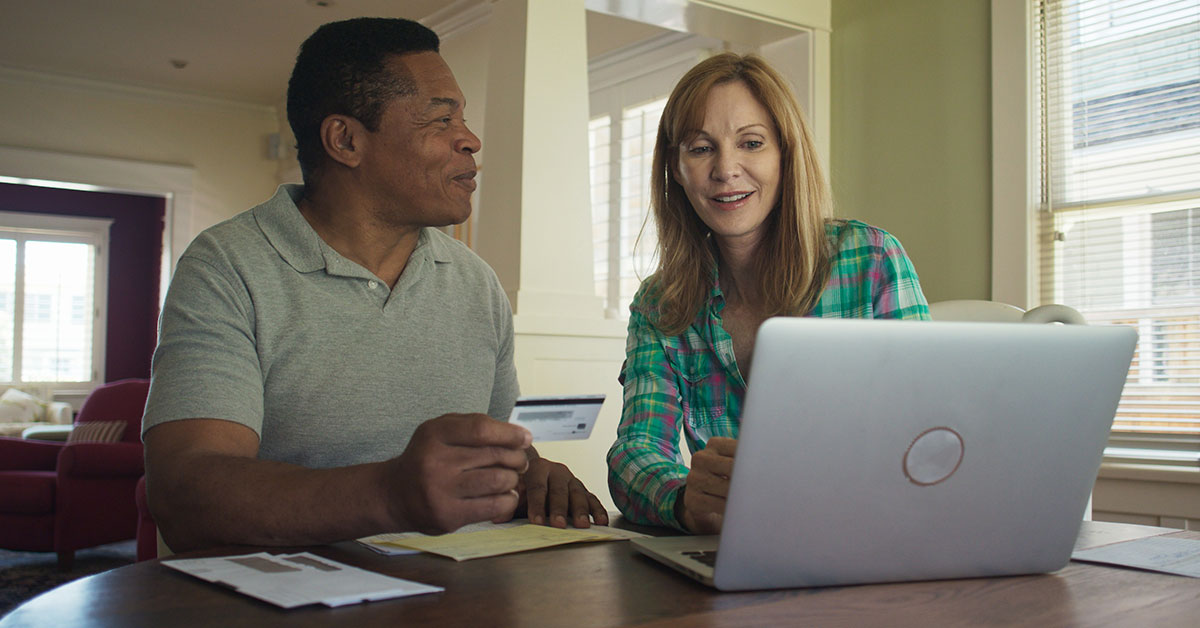 Happy mature couple pays some online bills with a credit card.