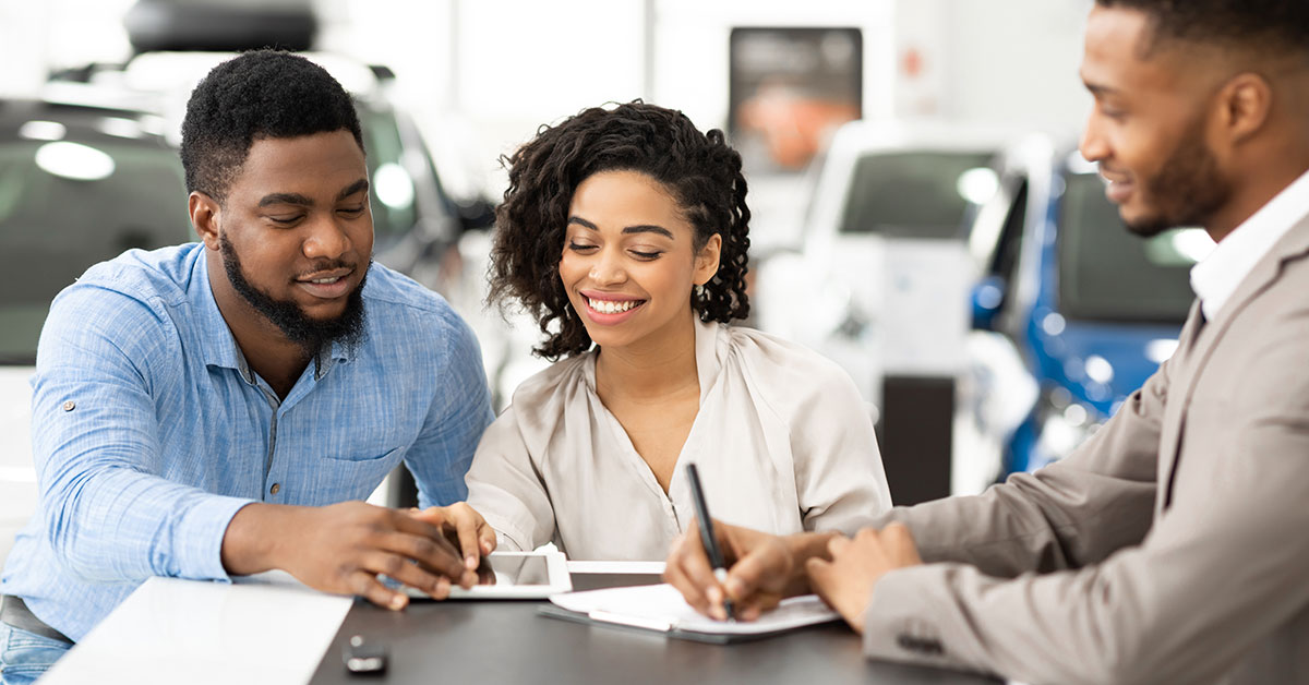 A man and a woman working with a car salesperson