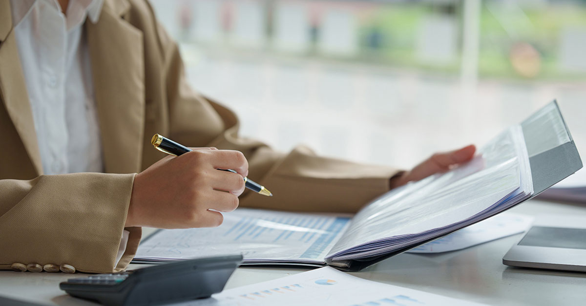 Lender at table, reviewing proof of income documents needed to apply for a mortgage