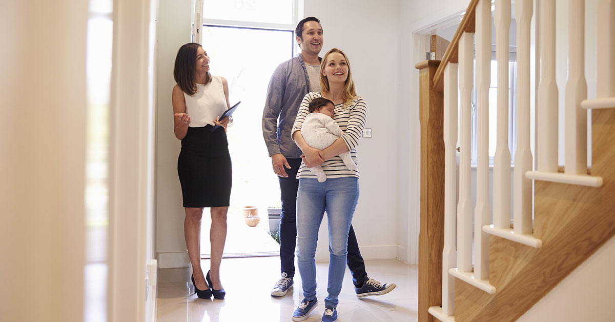 Couple with a baby walks through a new house with a real estate agent