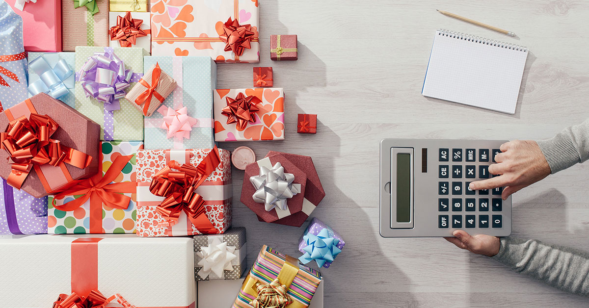 Person holds calculator while adding up the cost of wrapped presents.