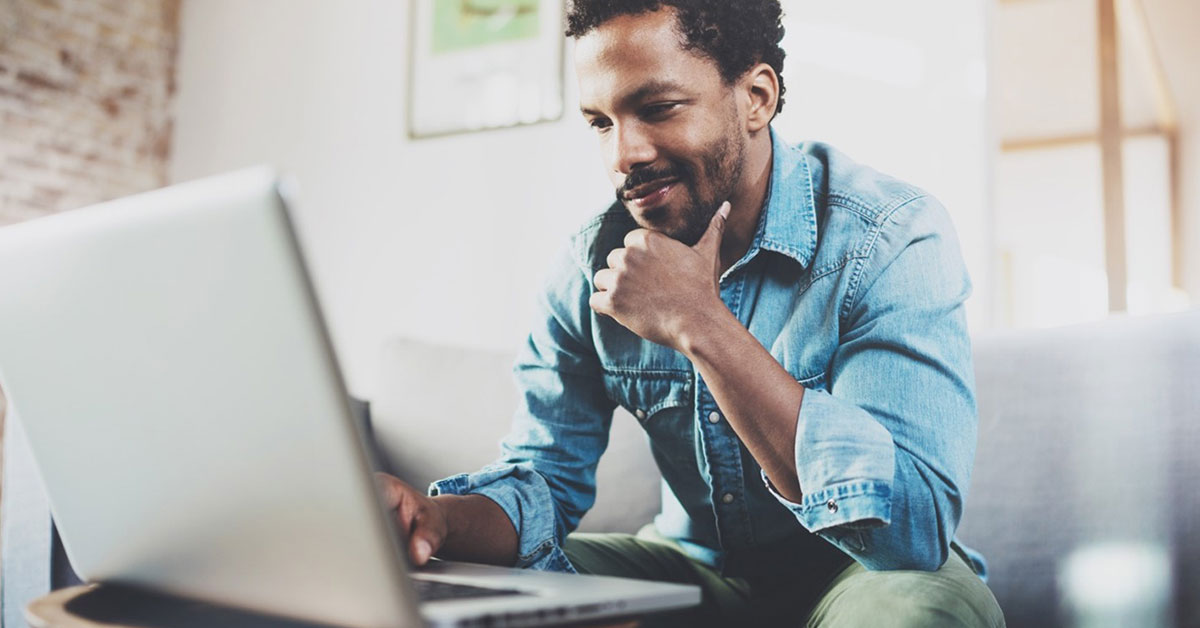 Man smiling on his computer reviewing his tax information