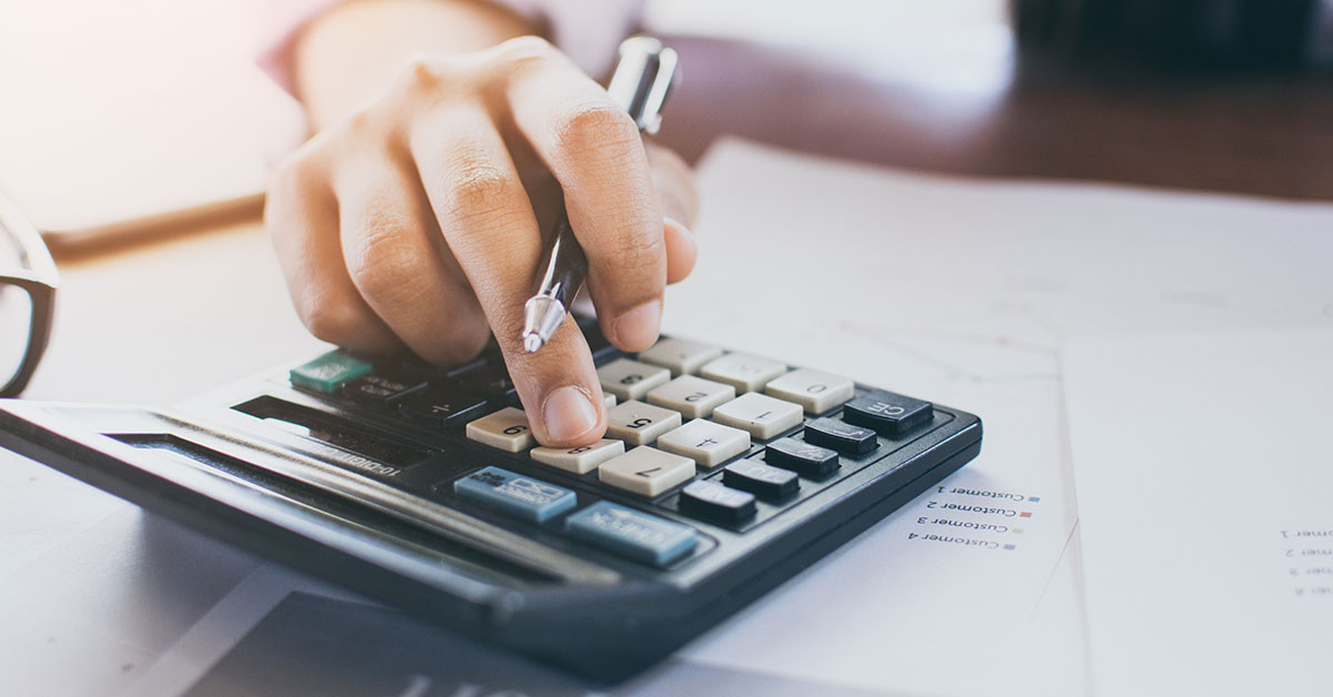 Close up of a man’s hands holding a pen and using a calculator