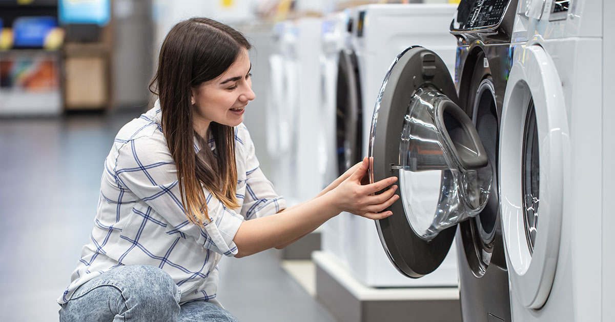 Woman looks at a new washing machine in the store.