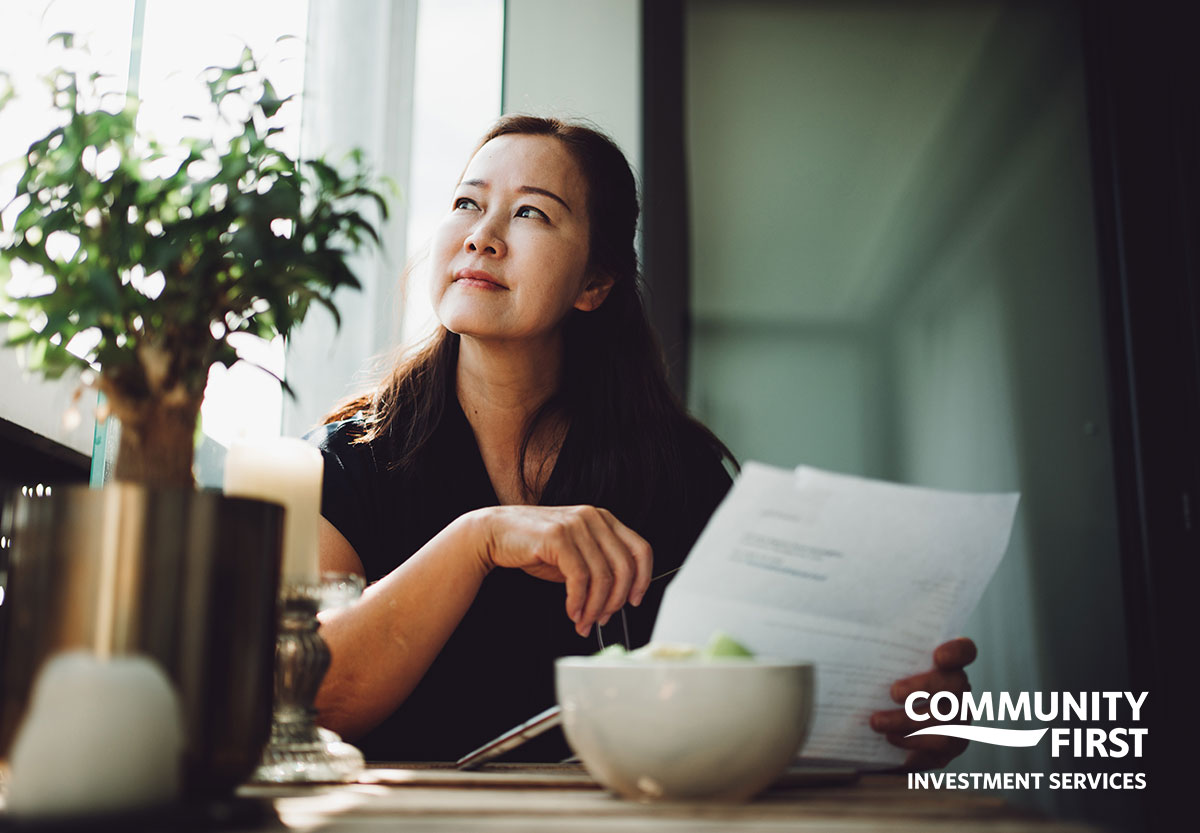 Woman with paperwork looking out window