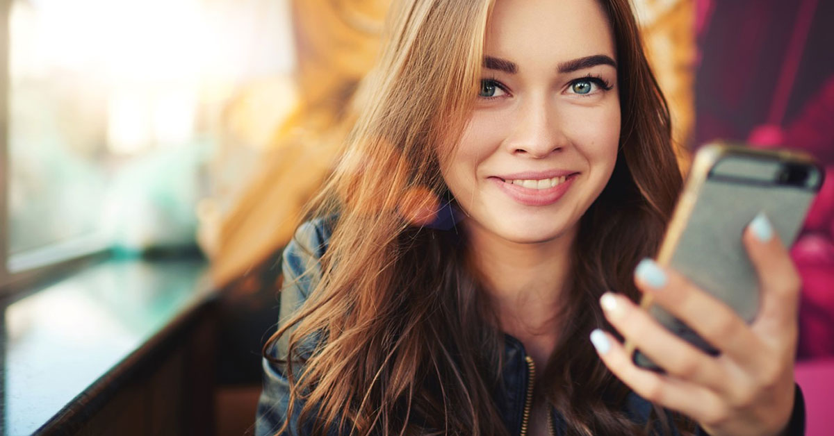 Happy young woman checks her bank account on her phone