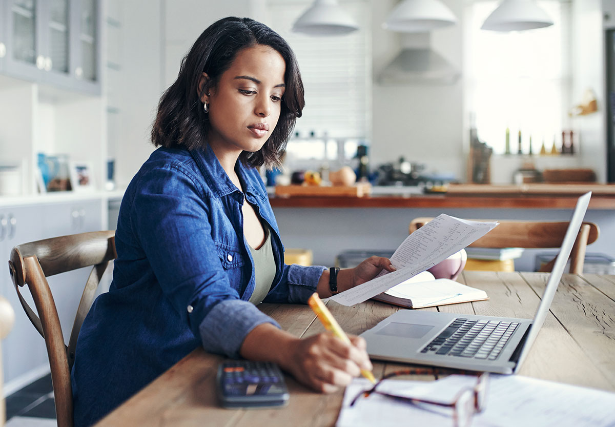 woman writing and using laptop
