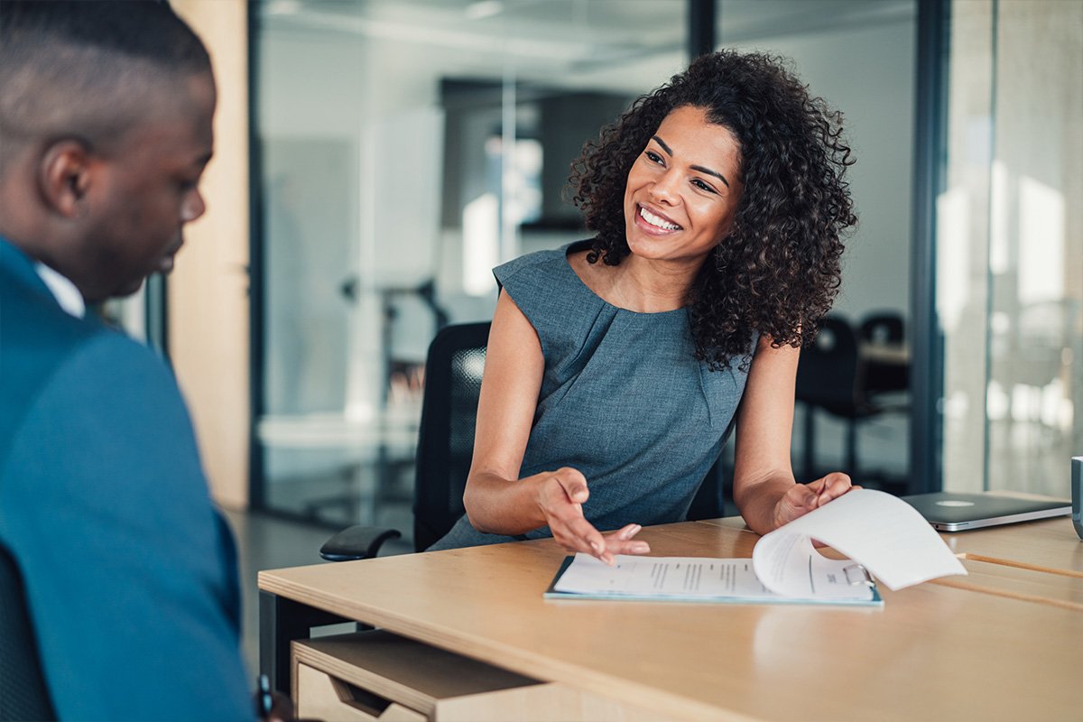 smiling woman at a table pointing to an investment plan