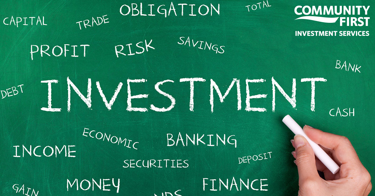 Hand with chalk writes investment-related words on a green chalk board
