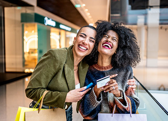 Two happy women with shopping bags and card