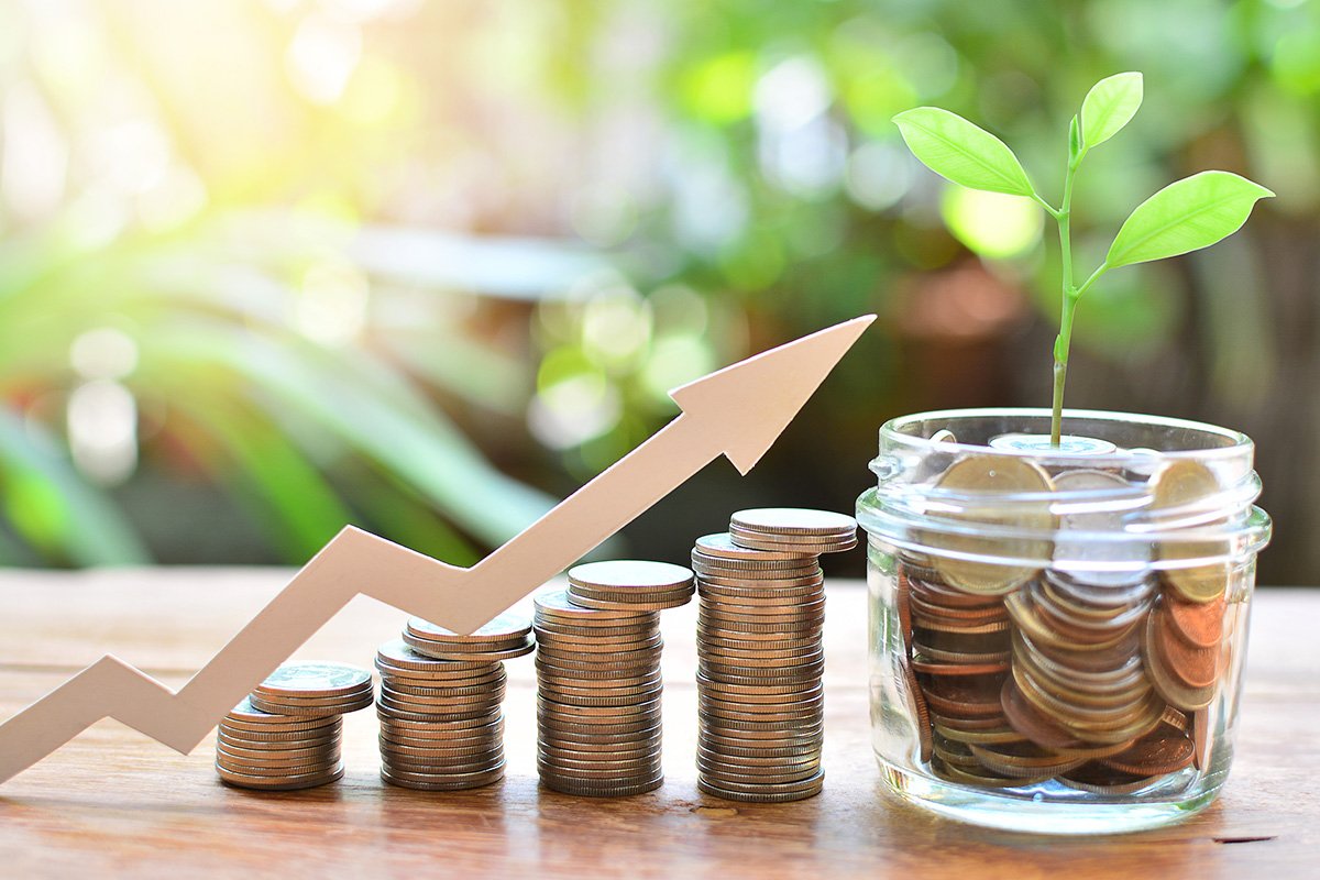 Coins on the table and a glass with a plant, and an arrow pointing upwards.