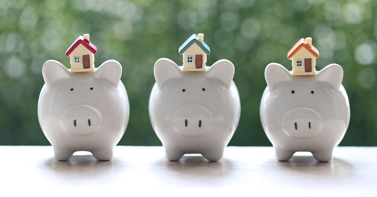 Three white piggy banks with small houses balanced on top of them