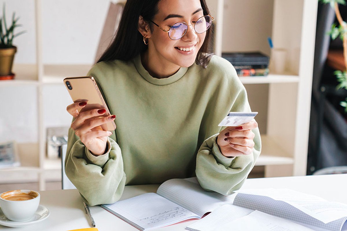 A girl with a phone in one hand and the other hand holds her credit card.