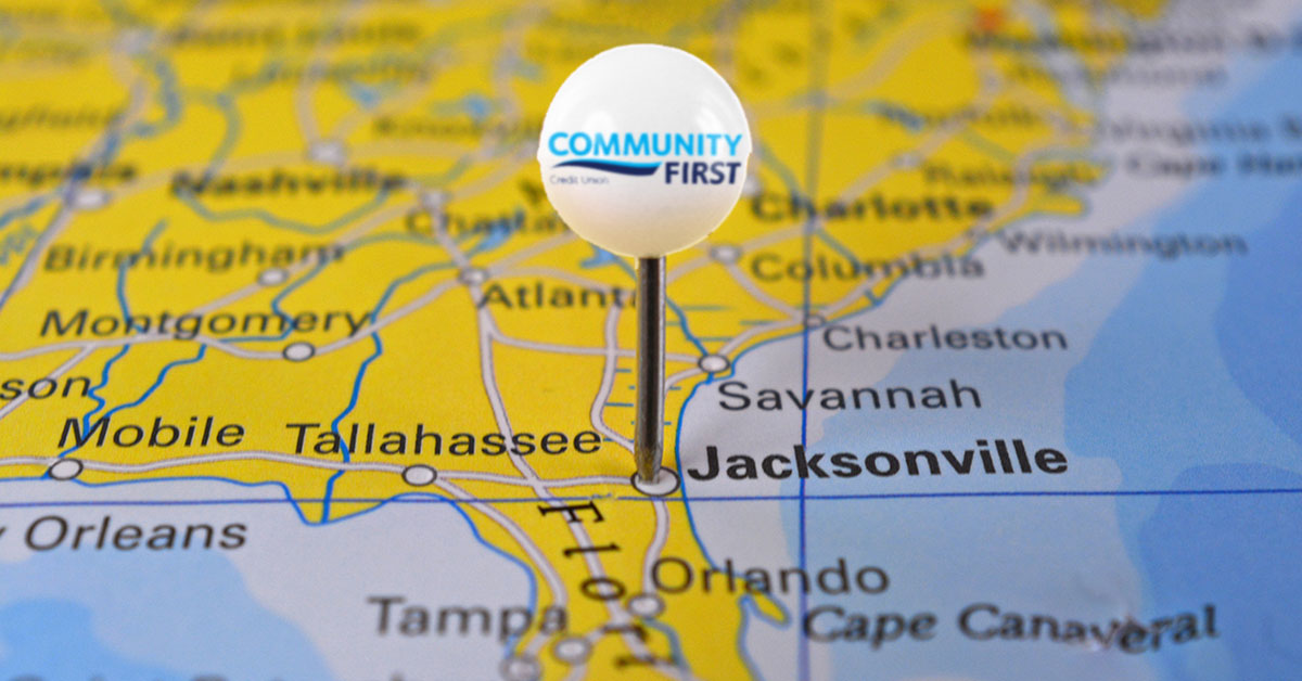 Close-up view of a yellow United States map, focused on a large, white, round pushpin with the Community First Credit Union logo over Jacksonville, Florida