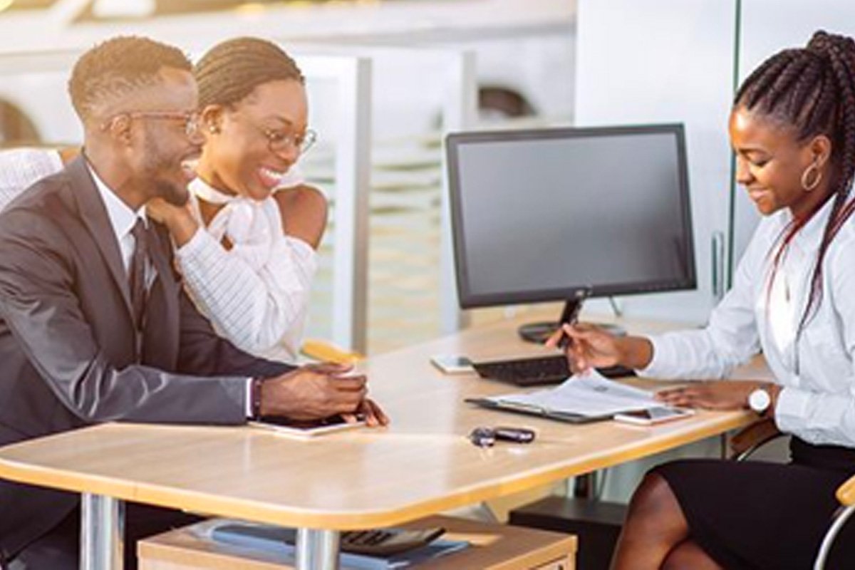 man and woman conversing with a female executive who is reviewing a document