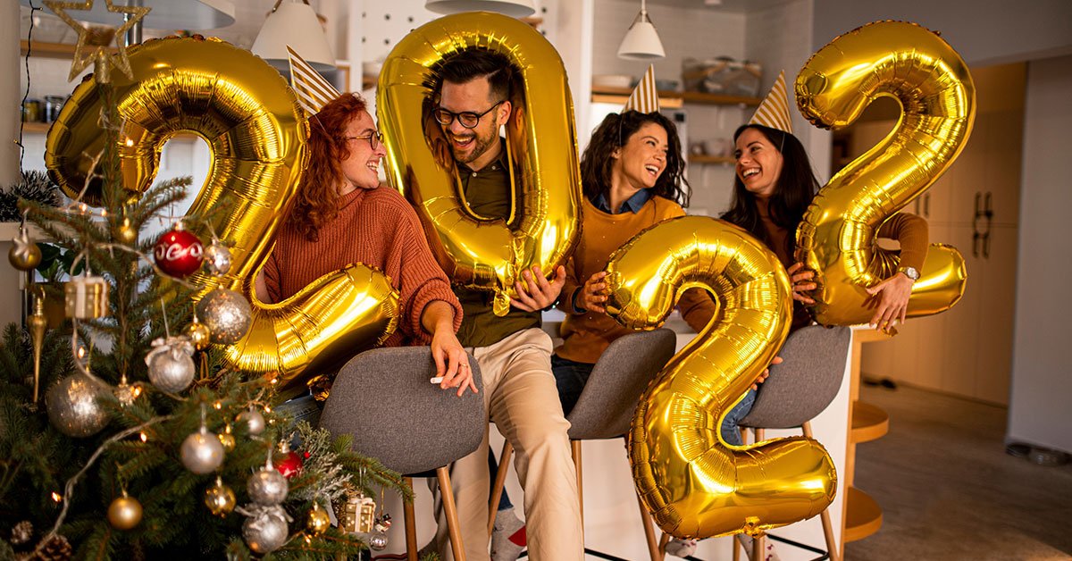 Four friends welcoming in the New Year holding 2022 balloons