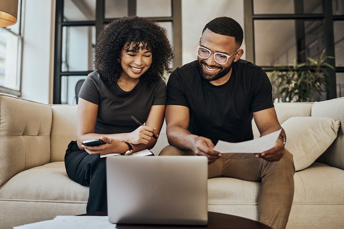 couple on a couch smiling at a laptop