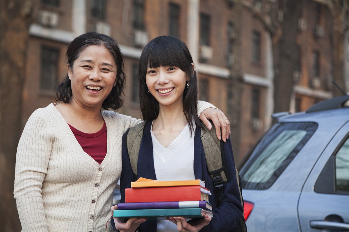 Mother with daughter smiling while carrying some red books.