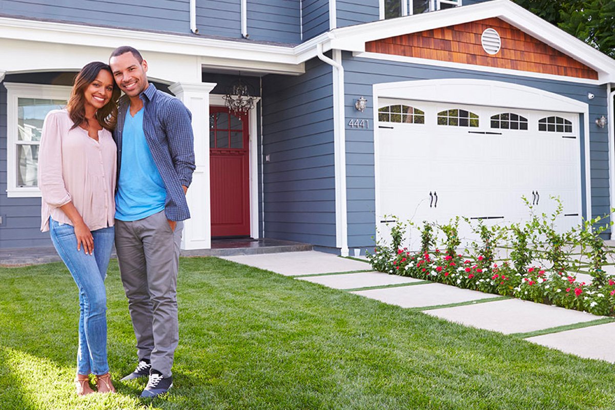 A couple hugging next to their house