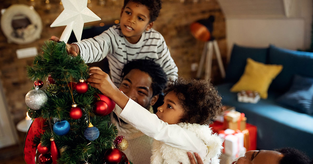 Family of four put the star on top of their Christmas tree.