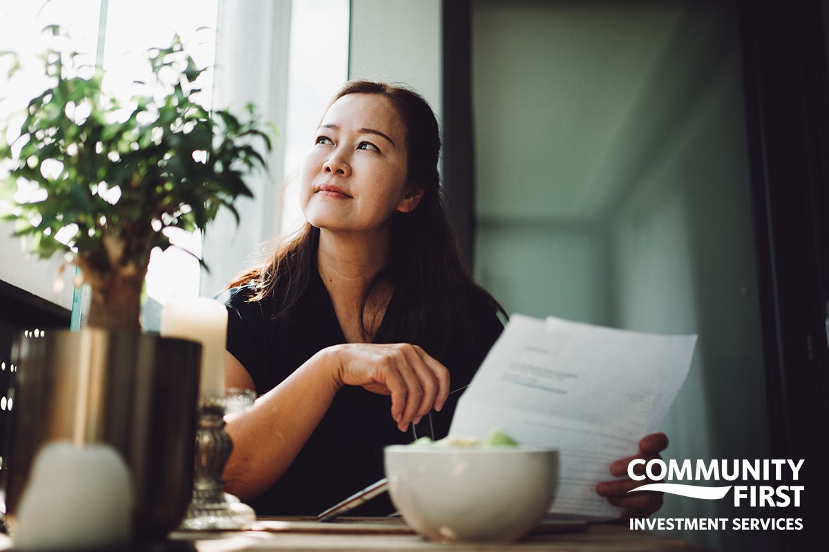 Woman with paperwork looking out a window