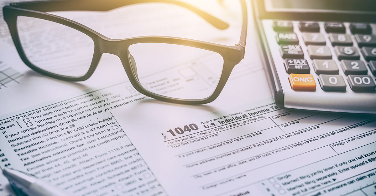 Tax forms laid out on a desk next to a pen and calculator