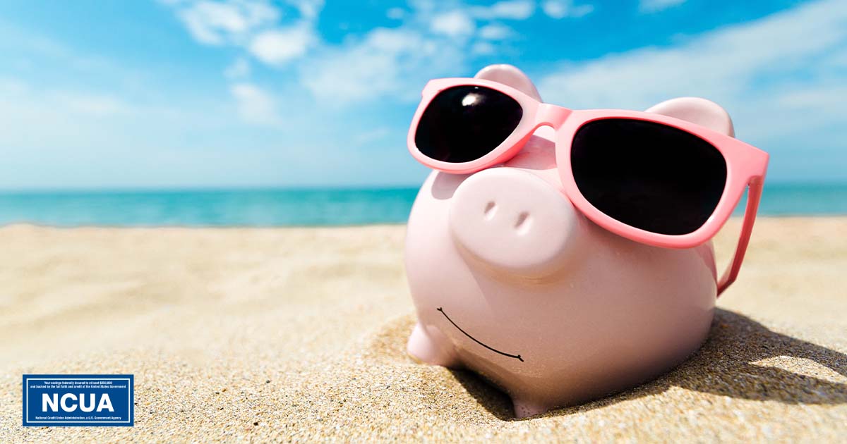 a piggy bank on the beach wearing sun glasses