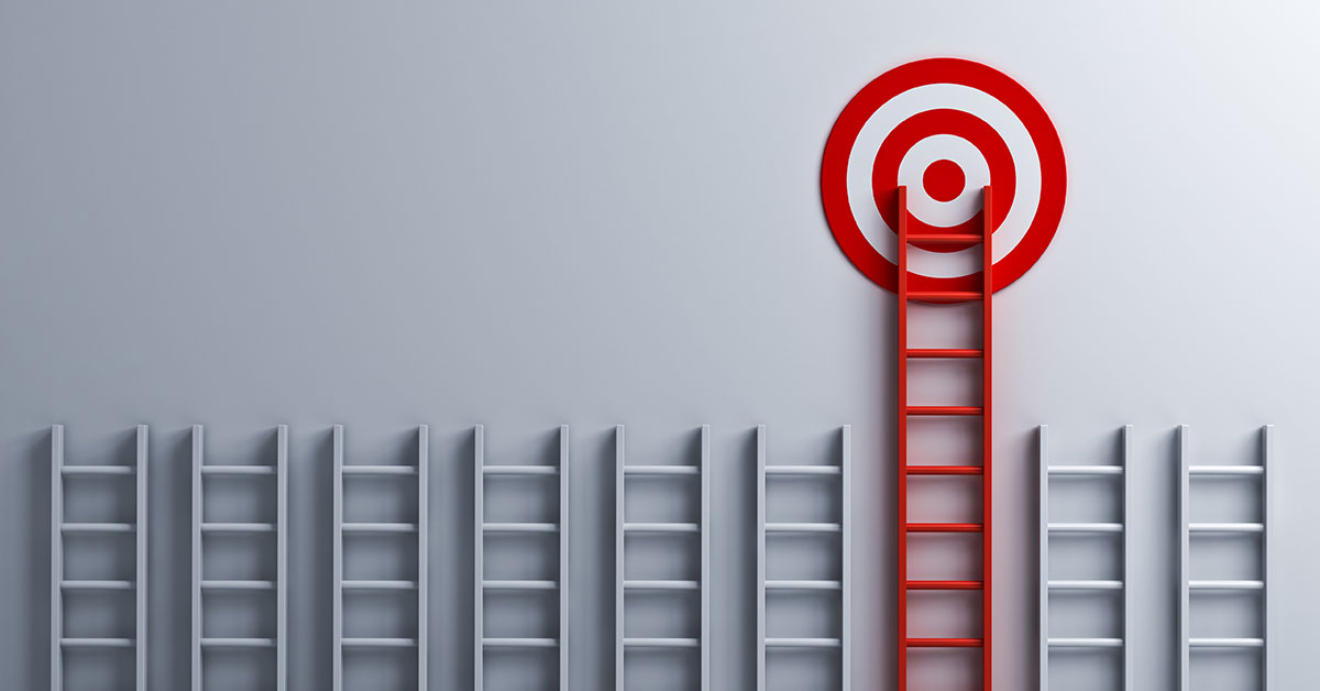 Ladders lined up in a row against a wall with one taller red ladder leading to a red target