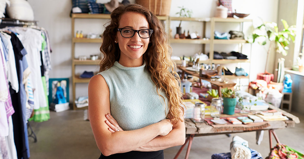 Smiling owner of boutique fashion store in front of the merchandise.