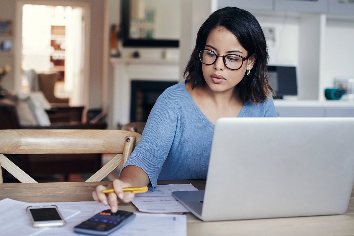 Woman working on a laptop and calculating financials.