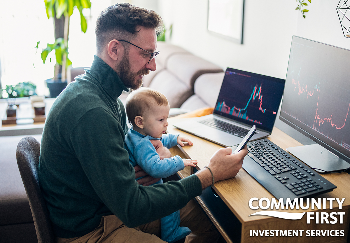 Man with Baby Looking at Phone with Laptop