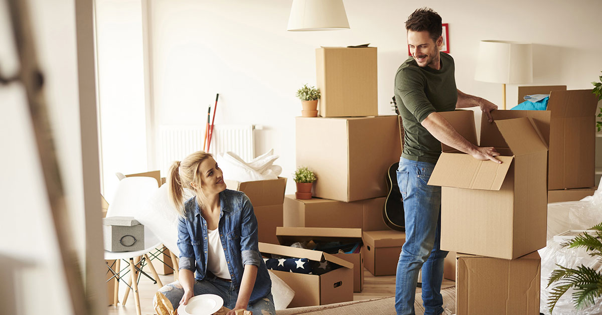 Young couple unpacks boxes with their dog