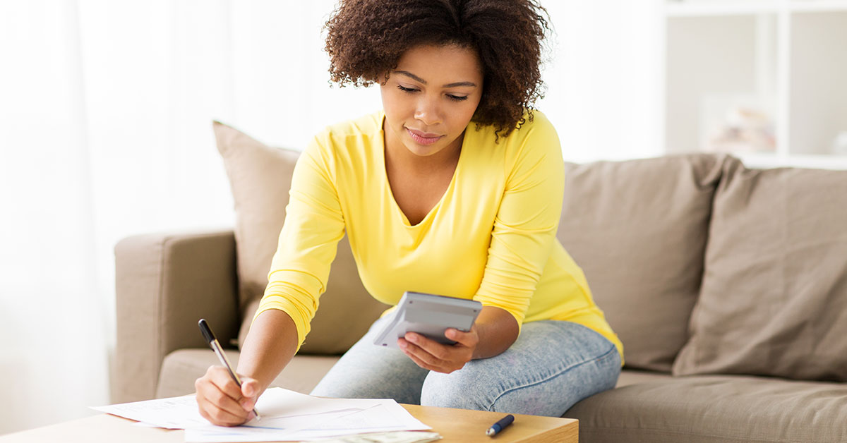 A woman using a calculator and writing down the results