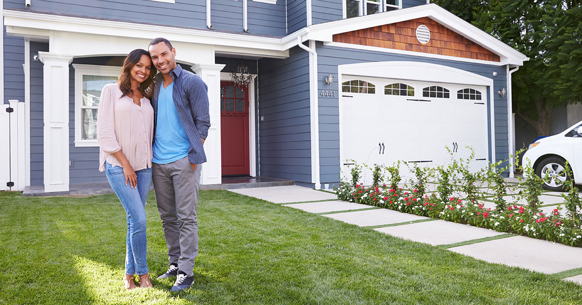 Happy young couple standing in front of their new home