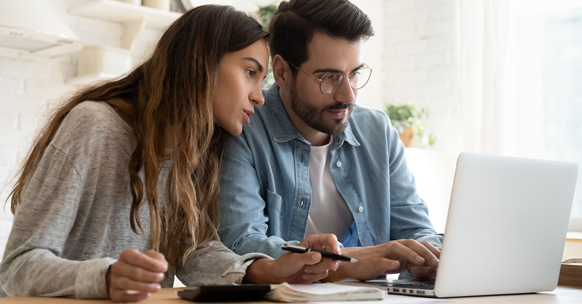 A couple goes over their financial documents on a laptop.